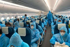 Tất cả hành khách được phát và phải mặc đồ bảo hộ trong suốt chuyến bay từ nước ngoài - nơi có dịch COVID-19 về Việt Nam. (Ảnh: CTV/Vietnam+)