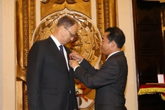 Thứ trưởng Bộ Ngoại giao Việt Nam Tô Anh Dũng gắn Huân chương Hữu nghị của Chủ tịch nước cho ông Christian Berger. (Ảnh: Dương Giang/TTXVN)