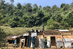 Cán bộ, chiến sỹ đồn biên phòng cửa khẩu Lóng Sập giúp người dân sửa lại nhà. (Ảnh: Hữu Quyết/TTXVN) 