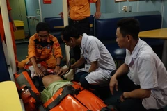 Chăm sóc y tế cho nạn nhân khi được đưa lên tàu SAR 412. (Ảnh: TTXVN)