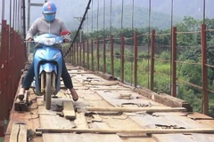 Trước khi sửa chữa, người dân lưu thông khó khăn trên cầu treo xuống cấp. (Ảnh: Thanh Hải/TTXVN)