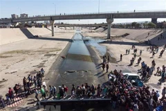 Người di cư Trung Mỹ vượt đoạn sông Tijuana để tới cửa khẩu El Chaparral, gần biên giới Mỹ-Mexico. (Ảnh: AFP/TTXVN)