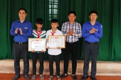 Trao bằng khen của Tỉnh đoàn và tiền thưởng cho hai em học học sinh Nguyễn Văn Chương và học sinh Nguyễn Phi Anh. (Ảnh: Phan Quân/TTXVN) 