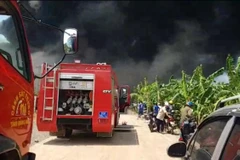 Xe chuyên dụng cùng lực lượng phòng cháy chữa cháy tiếp cận hiện trường tham gia dập lửa. (Ảnh: Sỹ Tuyên/TTXVN)