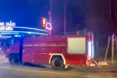 Lực lượng chức năng điều xe cứu hỏa đến hiện trường khống chế đám cháy không cho cháy lan sang cây xăng gần bên. (Ảnh: Nguyễn Văn Việt/TTXVN)