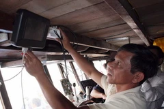Lắp đặt thiết bị kết nối vệ tinh VMS cho tàu cá. (Ảnh: Trần Lê Lâm/TTXVN)