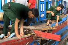 Lực lượng biên phòng đo đạc vết thủng trên mạn tàu. (Ảnh: Trịnh Duy Hưng/Vietnam+) 