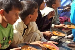 Trẻ em Pakistan nhận thức ăn từ thiện bên ngoài một cửa hàng ăn ở Karachi. (Nguồn: AFP/TTXVN)