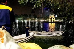 Chuẩn bị bãi cát nhân tạo dưới chân tháp Rùa để đón "cụ" Rùa lên chữa bệnh. (Ảnh: Quý Trung/TTXVN)