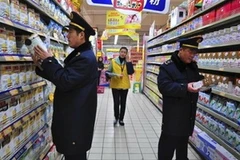 Cán bộ quản lý thị trường Trung Quốc kiểm tra sữa bột bày bán tại siêu thị. (Nguồn: AP)