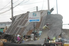 Người dân đang thu dọn mái tôn bị sập. (Ảnh: Lê Linh/Vietnam+)