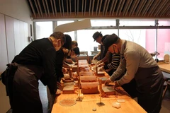 Các du khách trải nghiệm kỹ thuật đúc thiếc ở Công ty TNHH Nousaku. (Ảnh: Đào Thanh Tùng/TTXVN)