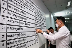 Nhân viên NEC niêm yết kết quả xếp thứ tự 18 chính đảng tham gia tổng tuyển cử năm 2023. (Ảnh: Huỳnh Thảo/ TTXVN)