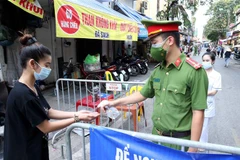 Người dân vào mua đồ thiết yếu tại chợ Đồng Xuân được lực lượng chức năng yêu cầu rửa tay sát khuẩn ngày 24/7/2021. (Ảnh: Phạm Kiên/TTXVN)