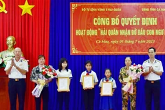 Lãnh đạo Bộ Tư lệnh Vùng 5 Hải quân trao quyết định cho.gia đình ngư dân có con được nhận đỡ đầu. (Ảnh: Huỳnh Anh/TTXVN)