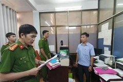 Công an tỉnh Quảng Ngãi đọc Quyết định khởi tố Bùi Mạnh Tường (sinh năm 1973), nhân viên Văn phòng đăng ký đất đai tỉnh Chi nhánh thành phố Quảng Ngãi. (Ảnh: TTXVN)