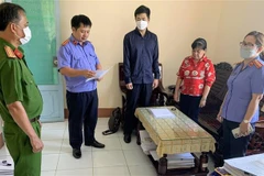 Cơ quan điều tra Viện Kiểm sát nhân dân Tối cao tống đạt Quyết định khởi tố bị can đối với bị can Nguyễn Thị Ngọc Tuyền (áo đỏ), nguyên thủ quỹ Chi cục Thi hành án dân sự huyện Thới Lai, thành phố Cần Thơ. (Ảnh: TTXVN phát)