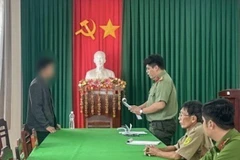 Cơ quan Công an tống đạt quyết định xử phạt đối với L.V.T. (Ảnh: TTXVN phát)