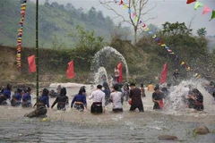 Bà con dân bản và du khách cùng nhau ra suối thực hiện nghi thức té nước với mong muốn gặp nhiều may mắn trong Năm mới. (Ảnh: Xuân Tư/TTXVN)