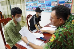 Lực lượng chức năng rà soát thông tin của các công dân vừa tiếp nhận từ lực lượng chức năng Campuchia. (Ảnh: Thanh Tân/TTXVN)