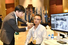 Một người đàn ông dùng thử hệ thống chẩn đoán siêu âm dựa trên công nghệ AI tại Hội nghị, ngày 26/6. (Ảnh: Tân Hoa xã)