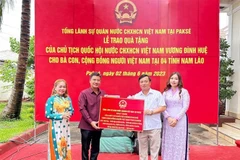 Đại diện Tổng Lãnh sự quán Việt Nam tại Pakse trao quà của Chủ tịch Quốc hội cho đại diện cộng đồng người Việt tại tỉnh Sekong. (Ảnh: TTXVN phát)