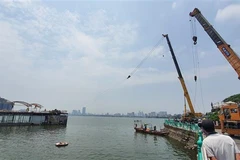 Du thuyền (đã bị chìm một phần) của Công ty cổ phần Sông Potomac đang được lực lượng chức năng kéo vào gần bờ rồi tiến hành tháo dỡ, di chuyển. (Ảnh Minh Nghĩa/TTXVN)