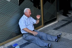 Một người dân Hy Lạp ngồi bên ngoài chi nhánh ngân hàng ở Thessaloniki chờ rút tiền. (Nguồn: AFP/TTXVN) 