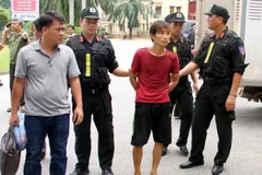 Lực lượng công an áp giải nghi can Đặng Văn Hùng. (Ảnh: Thế DuyệtTTXVN) 