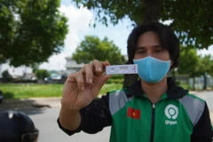 Đối tác tài xế của Gojek hào hứng khoe kết quả âm tính khi xét nghiệm nhanh COVID-19. (Ảnh: T.U/Vietnam+)