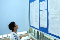 Thí sinh xem thủ tục làm hồ sơ xét tuyển vào đại học. (Ảnh: Minh Sơn/Vietnam+)