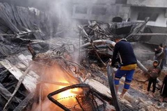 Lính cứu hỏa Palestine dập đám cháy tại một tòa nhà sau vụ không kích của Israel. (Ảnh tư liệu: AFP/TTXVN)