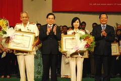 Chủ tịch nước và Bí thư Thành ủy trao tặng danh hiệu anh hùng cho Đại tá Lê Văn Nón và Thượng tá Phan Thị Ngọc Tươi. (Ảnh: Hoàng Hải/TTXVN)