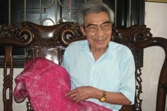 Nghệ nhân Nguyễn Hữu Chỉnh giới thiệu mẫu lụa hoa ban do ông thiết kế. (Ảnh: Thiên Linh/ Vietnam+)