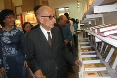 Giáo sư, Anh hùng lao động Vũ Khiêu cùng độc giả Thủ đô tham quan tủ sách. (Ảnh: Thiên Linh/ Vietnam+)