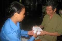 Ông Tưởng giao thẻ cử tri cho trưởng thôn Vực. (Ảnh: Thiên Linh/Vietnam+)