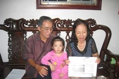 Ông Nhược và vợ đang đọc cho cháu nghe một bài báo viết về đoàn tàu không số. (Ảnh: Thiên Linh/ Vietnam+).