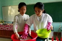 Hai nữ sinh thực hiện công đoạn sản xuất giấy theo phương pháp thủ công trong phòng thí nghiệm.