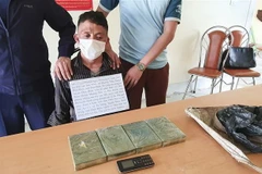 Đối tượng Thào A Khứ cùng vật chứng 4 bánh heroin. (Ảnh: TTXVN phát)
