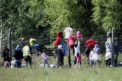 Người di cư vượt qua hàng rào tại khu vực làng Roszke, biên giới Hungary-Serbia. (Ảnh: AFP/TTXVN)