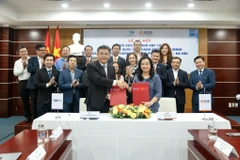 Tiến sỹ Ngô Thu Hà - Tổng Giám đốc SHB và Phó giáo sư, Tiến sỹ Nguyễn Minh Tâm - Phó Giám đốc Đại học Quốc gia Thành phố Hồ Chí Minh trao thỏa thuận hợp tác. (Ảnh: Vietnam+)