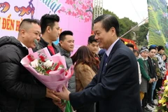 Chủ tịch UBND tỉnh Hà Giang Nguyễn Văn Sơn tặng hoa cho những du khách đầu tiên “xông đất” du lịch Hà Giang năm 2021. (Ảnh: TTXVN phát)