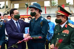 Bí thư Thành ủy Hà Nội Vương Đình Huệ tặng hoa, động viên các tân binh lên đường nhập ngũ. (Ảnh: TTXVN)
