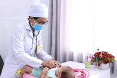 Các bác sỹ đang tái khám cho bệnh nhi. (Ảnh: TTXVN phát)