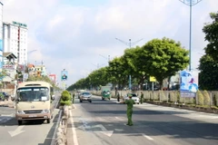 Lực lượng chức năng kiểm soát chặt các phương tiện lưu thông trên đường Trường Chinh, đoạn qua quận 12. (Ảnh: Tiến Lực/TTXVN)