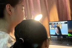 Phụ huynh cùng học sinh lớp 1 (năm học 2021-2022) của trường Tiểu học Thăng Long, quận Hoàn Kiếm trao đổi cùng giáo viên chủ nhiệm lớp để làm quen với việc học trực tuyến của trẻ. (Ảnh: TTXVN phát)