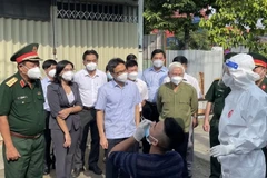 Phó Thủ tướng Vũ Đức Đam kiểm tra công tác test nhanh COVID-19 và khuyến khích người dân tự thử xét nghiệm. (Ảnh: Huyền Trang/TTXVN)