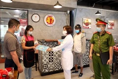 Ngay từ sớm, lực lượng chức năng phường Hàng Buồm, quận Hoàn Kiếm, Hà Nội, tăng cường nhắc nhở, tuyên truyền các cơ sở kinh doanh dịch vụ ăn uống không được nhận khách ăn uống tại cửa hàng mà chỉ được bán đồ mang về. (Ảnh: Phạm Kiên/TTXVN)
