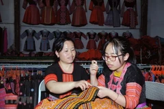 Chị Tráng Thị Dua (bên trái) truyền dạy nghề thêu, may truyền thống của đồng bào dân tộc Mông cho con gái. (Ảnh: Quang Quyết/TTXVN)