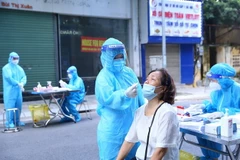 Lực lượng y tế lấy mẫu xét nghiệm sàng lọc SARS-CoV-2 cho người dân phường Nguyễn Du sáng 30/9. (Ảnh: Hoàng Hiếu/TTXVN)
